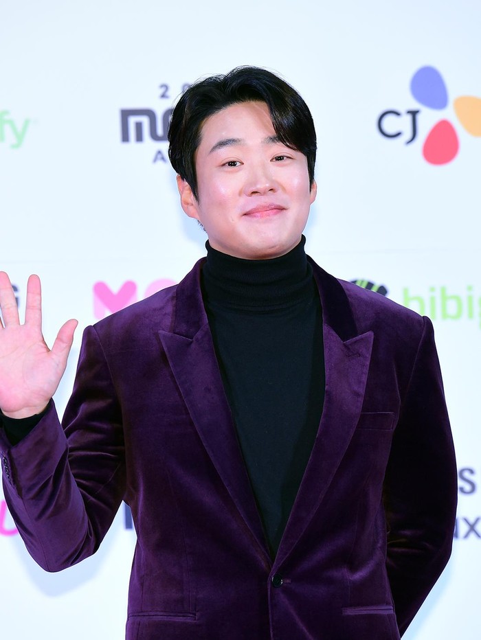 Bintang serial Netflix Mask Girl (2023), Ahn Jae Hong, tampil penuh percaya diri dalam balutan velvet suit berwarna ungu yang dipadukan dengan turtle neck top berwarna hitam./ Foto: soompi.com