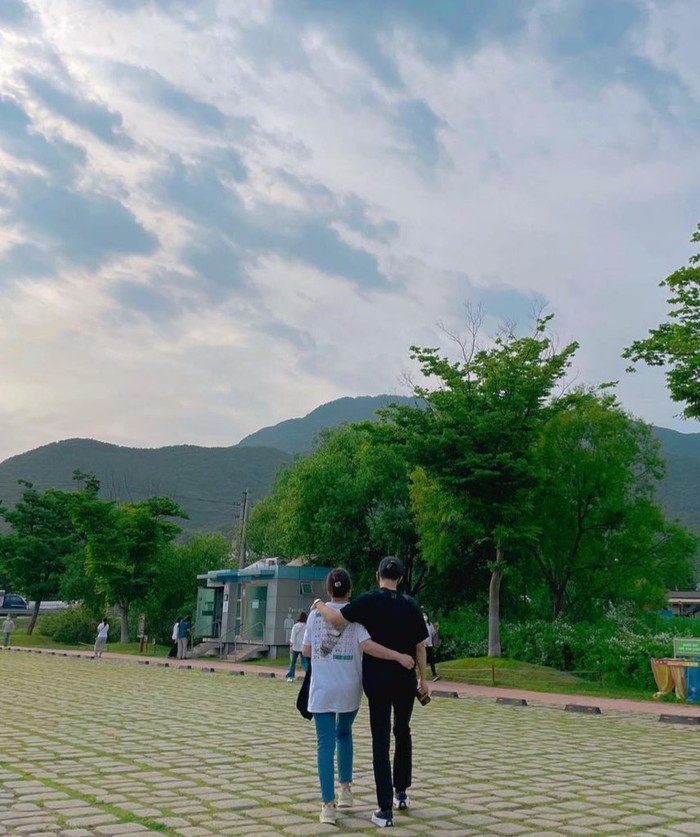 Tampak dari belakang, sang Adik memotret candid kakak dan ibunya, Terlihat Yunhyeong sedang merangkul sang Ibu sambil berjalan. Mesra banget, ya! /Foto: Instagram Story/_eunjinsong