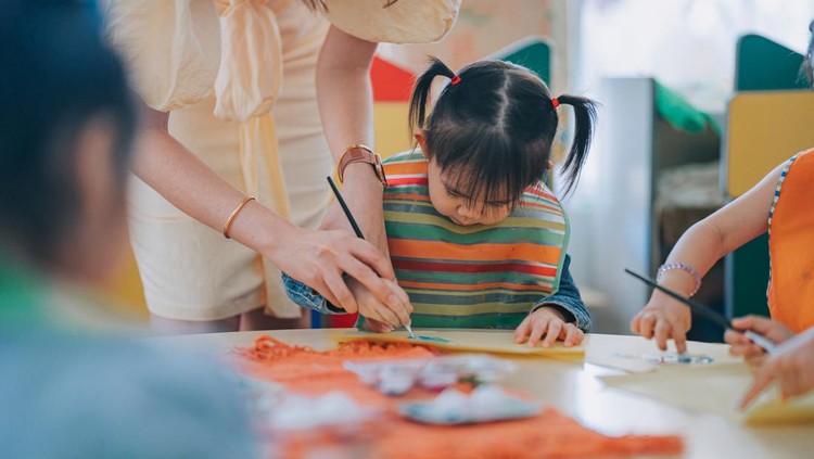 asian chinese Montessori preschool female teacher guiding her student drawing in classroom