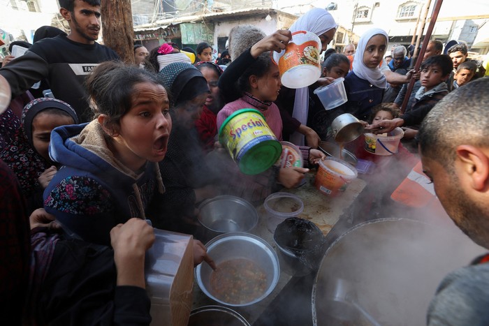 A Palestinian child reacts, while people gather to get their share of charity food offered by volunteers, amid food shortages, as the conflict between Israel and the Palestinian Islamist group Hamas continues, in Rafah, in the southern Gaza Strip, December 2, 2023. REUTERS/Ibraheem Abu Mustafa