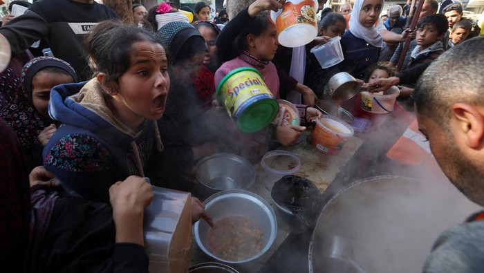 A Palestinian child reacts, while people gather to get their share of charity food offered by volunteers, amid food shortages, as the conflict between Israel and the Palestinian Islamist group Hamas continues, in Rafah, in the southern Gaza Strip, December 2, 2023. REUTERS/Ibraheem Abu Mustafa