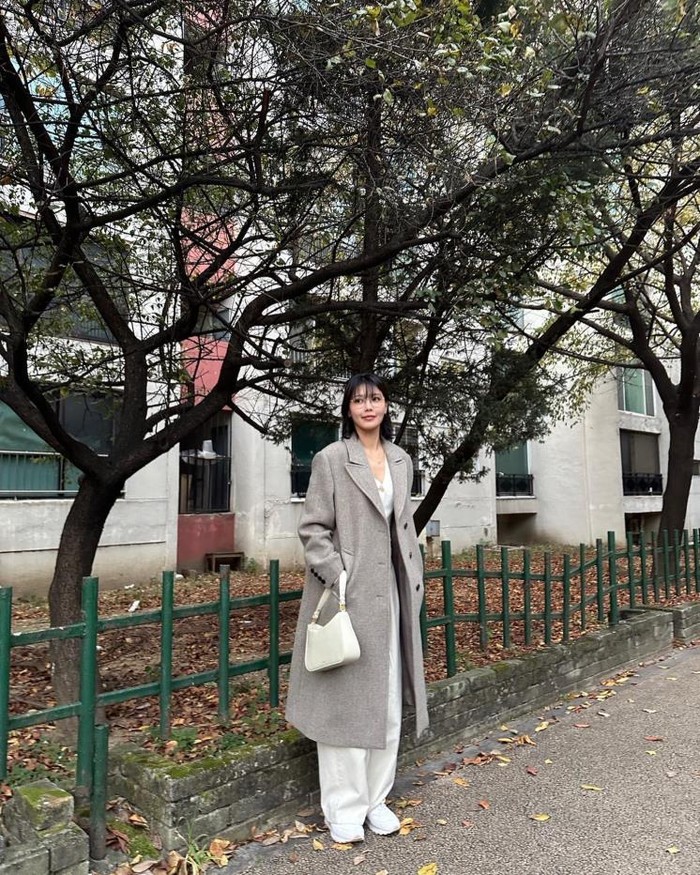 Sooyoung mengenakan coat single-breasted berwarna abu-abu muda yang membuatnya terlihat trendy. Ia melengkapi tampilannya dengan sweater, celana, tas, dan sepatu kets berwarna putih senada./ Foto: Elle.co.kr