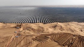 In this photo taken on December 9, 2023, vehicles prepare land for new solar panels next to a field of solar panels during construction at the Ningxia Tengger Desert New Energy Base in Chinas northern Ningxia region. (Photo by AFP) / China OUT