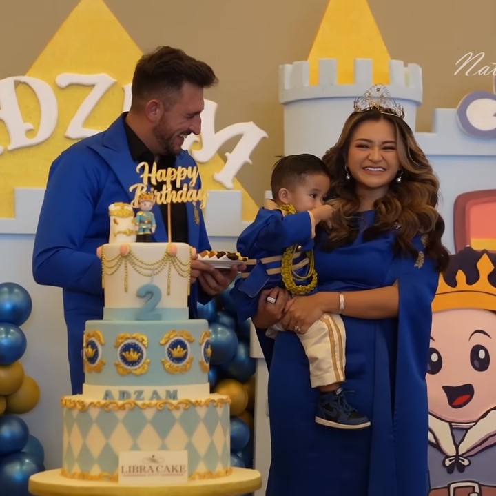 <p>Adzam sangat tampan mengenakan setelah warna biru tua. Sementara itu, Nathalie mengenakan gaun warna senada dengan sentuhan <em>gold</em> dan mahkota yang cantik. (Foto: YouTube Nathalie Holscher)</p>