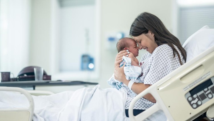 Newborn baby in delivery room.Blurred Mother background giving birth to a baby and kiss her baby. Woman pregnant patient in a hospital. Parent and infant first moments of bonding.