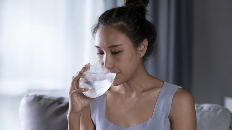 Young Asian woman drinking pure water with ice from glass. Female drinking from a glass of water. Health care concept