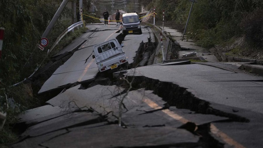 Bystanders look at damages somewhere near Noto town in the Noto peninsula facing the Sea of Japan, northwest of Tokyo, Tuesday, Jan. 2, 2024, following Monday's deadly earthquake. A series of powerful earthquakes that hit western Japan have damaged thousands of buildings, vehicles and boats. Officials warned that more quakes could lie ahead.  (AP Photo/Hiro Komae)