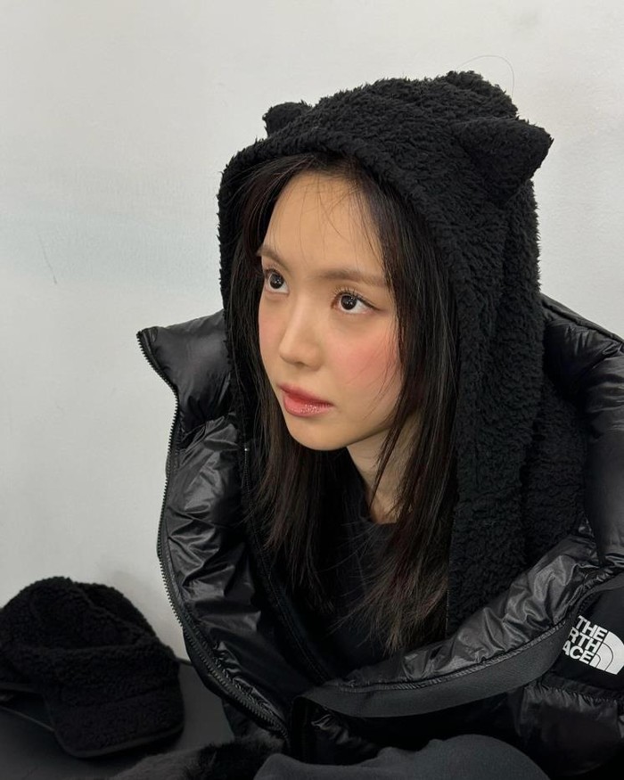 Son Na Eun terlihat kasual namun unik dalam penampilannya memakai topi hoodie hitam dengan telinga kucing. Ia berhasil memadukan kenyamanan dan gaya yang memikat, menciptakan tampilan yang stylish./ Foto: Elle.co.kr