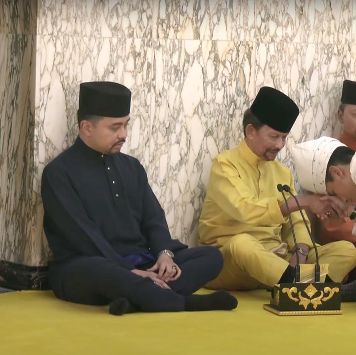 <p>Seperti proses adat di Tanah Air, Mateen sumkem pada Sultan Hassanal Bolkiah. Setelah mencium tangan, sang ayah membacakan doa dan harapan untuk pernikahan Pangeran Mateen. "Semoga Allah menkaruniakan keberkatan kepada kalian berdua, menyatukan kalian berdua dalam kebajikan," tuturnya. (Foto: YouTube RTB News)</p>