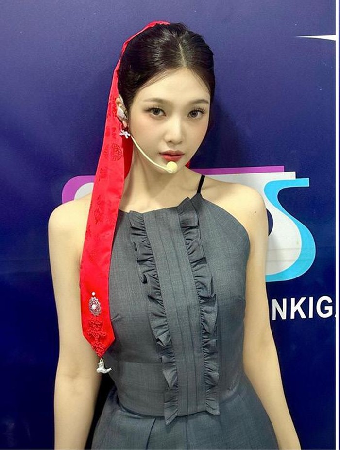 Joy menggunakan pita panjang dengan rambut yang diikat ekor kuda tinggi. Warna yang kontras antara rambut hitam dan pita merah cerah pada tampilannya sukses mencuri perhatian. / Foto: allurekorea.com