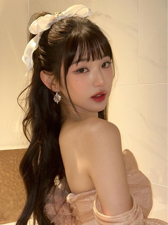 Wonyoung memamerkan rambut pita klasik yang memancarkan keindahan pada tampilannya. Rambutnya ditata tebal, setengah terikat dengan pita besar berwarna putih yang membuatnya terlihat seperti peri yang misterius./ Foto: allurekorea.com