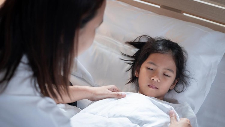 Sick asian child girl get sick and sleep on the bed, mother taking care and cover the blanket on her daughter at home.