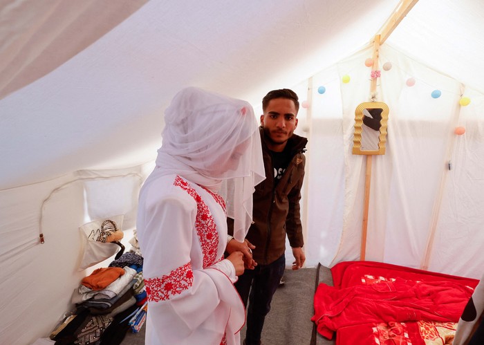 A Palestinian couple stands in a tent camp, amid the ongoing conflict between Israel and the Palestinian Islamist group Hamas, on their wedding day, in Rafah in the southern Gaza Strip, January 18, 2024. REUTERS/Mohammed Salem