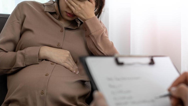 1449381819 The pregnant mother is discussing depression symptoms during pregnancy with a specialist doctor or psychiatrist. The future mom is unhappy, worried, and stressed. Mental health concept