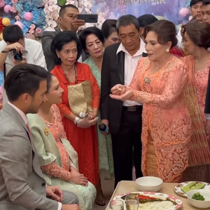 <p>Dalam acara Mambosuri ini, Mila dan suami mengikuti beberapa prosesi adat Batak. Dalam salah satu prosesi, tampak ibunda Mila, Jane Magdalena Baker, menyuapi putrinya dengan makanan. (Foto: Instagram @jscmila)</p>