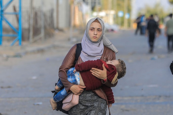 18 November 2023, Palestinian Territories, Gaza City: A woman carries a baby as Palestinian families flee Gaza City and other parts of northern Gaza towards the southern areas amid ongoing battles between Israel and the Palestinian Hamas Group.. Photo: Mohammed Talatene/dpa (Photo by Mohammed Talatene/picture alliance via Getty Images)
