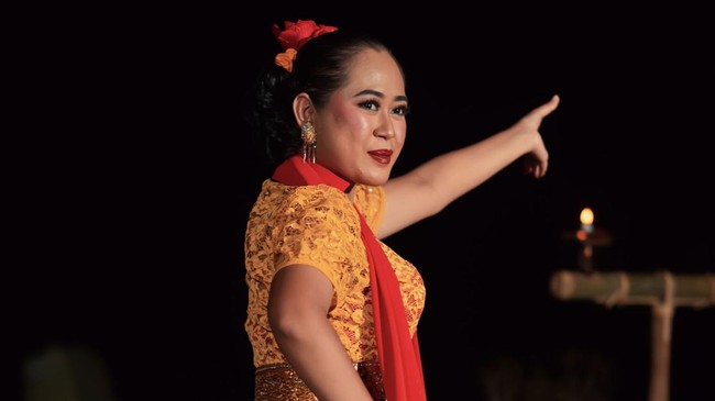Asian woman performing a traditional dance called jaipong in Indonesia with a yellow dress and red scarf at the dance festival