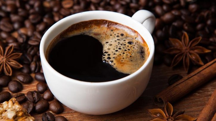 cup of black coffee and cinnamon sticks closeup