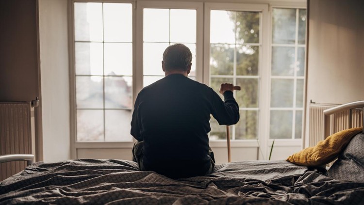 A lonely man is sitting on the bed