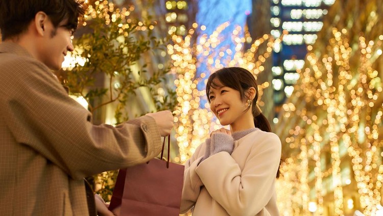 Man and woman holding gifts and a cityscape illuminated at night