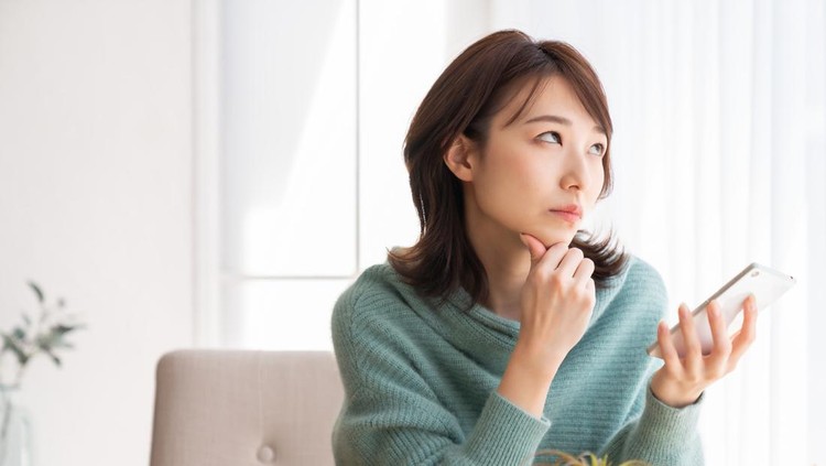 Young attractive Asian woman using a smartphone&comma;think&comma;