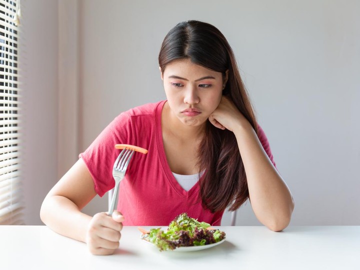 Seorang perempuan ragu ingin makan atau tidak karena diet OMAD