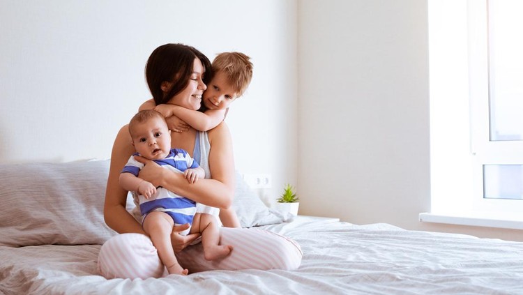 Portrait of mother with two sons in bedroom at home