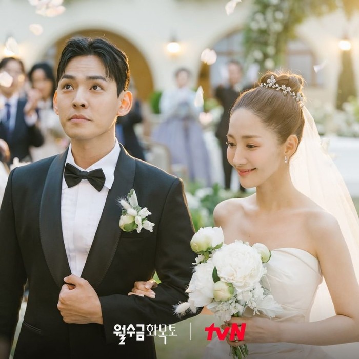 Masih dalam pernikahan yang sama. Sang Eun terlihat begitu manis dan fresh dengan gaun pengantinnya. Rambutnya yang dikuncir cepol dengan kain veil menjuntai membuat dirinya tampak elegan./Foto: tvN