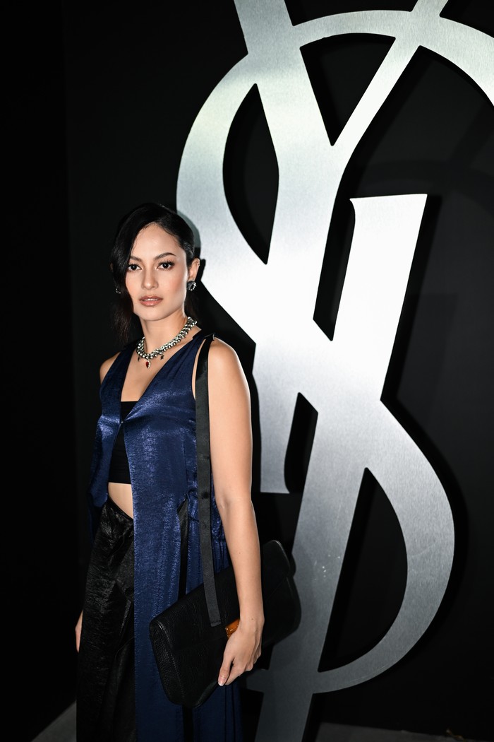 Meski meninggalkan perpaduan tekstur, sebuah look juga punya daya pikat dengan mengombinasi warna fashion items. Bra top dan rok asimetris hitam kian atraktif dengan lapisan outer panjang navy blue/ Foto: Courtesy of YSL/ Isac