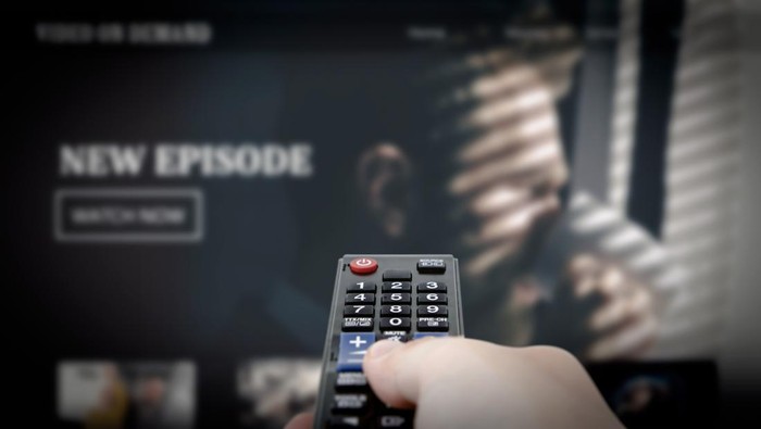 VOD service on television. Man watching TV, streaming service, video on demand, remote control in hand.