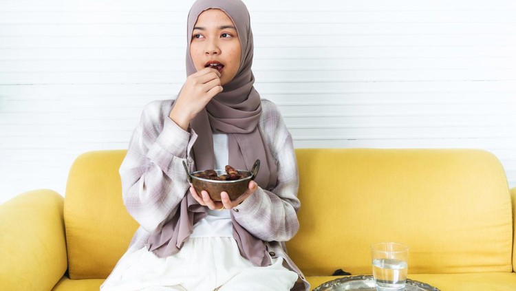 Young muslim woman eating date to break fast at home