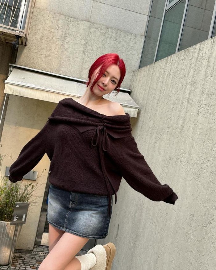 Rambut merah Yuna ITZY membuatnya terlihat mencolok, terutama tampilannya dengan sweater off-shoulder yang dilengkapi pita dan rok mini denim vintage. Ia juga melengkapinya dengan sepatu bot shearling ala Y2K yang manis./ Foto: Elle.co.kr