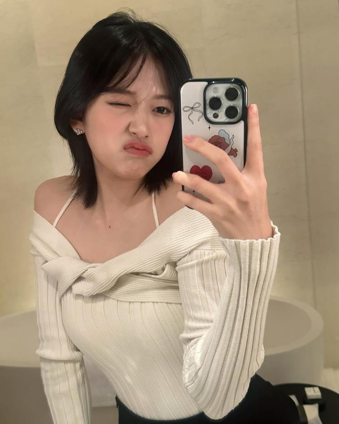 Yujin IVE dengan sempurna memilih atasan off-shoulder dengan strap bahu tipis dan detail twist di bagian dada untuk menciptakan tampilan yang serasi dengan rambut pendeknya. Ia berhasil menciptakan suasana glamor dalam outfit ini./ Foto: elle.co.kr