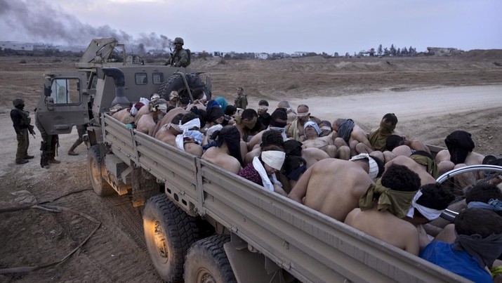 Tentara Israel berdiri di dekat truk yang berisi tahanan Palestina yang diikat dan ditutup matanya, di Gaza, Jumat, 8 Desember 2023. (AP Photo/Moti Milrod, Haaretz, File Foto)