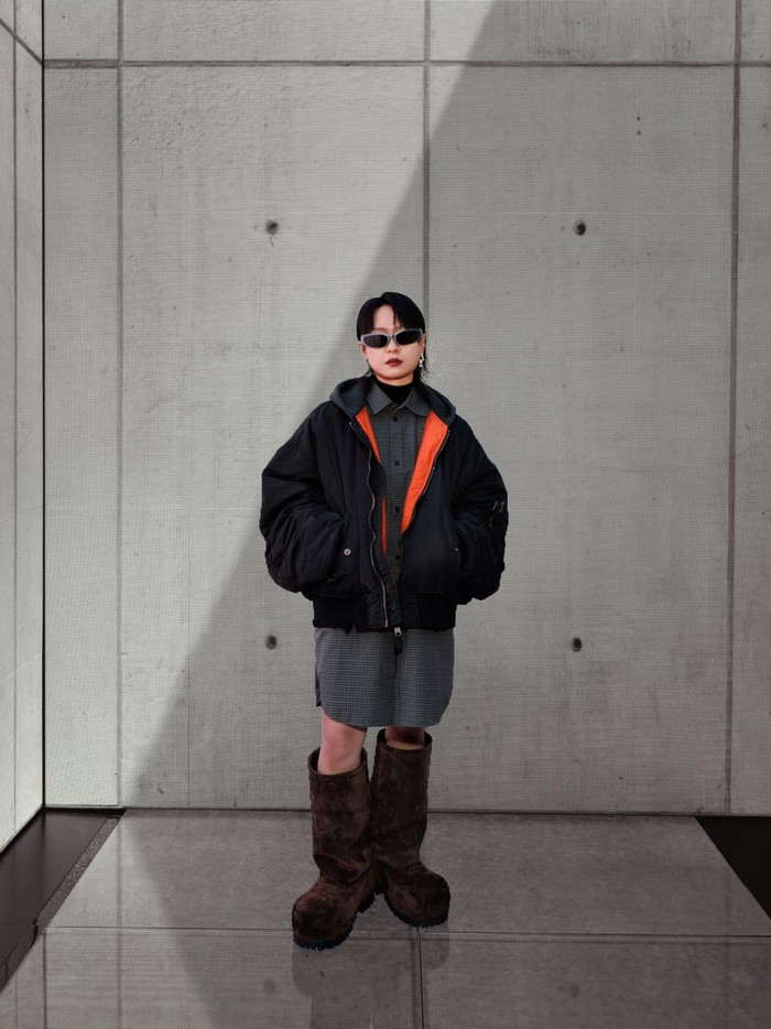 Turut hadir adalah penyanyi asal Tiongkok, Bibi Zhou, yang memesona berbalut shirt dress check ditumpuk jaket hitam. Chunky boots yang menyatu dalam look turut meningkatkan gayanya / Foto: Courtesy of Balenciaga