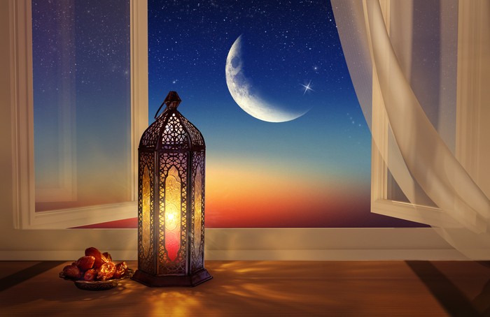 Ramadan lantern by the open window. Beautiful Greeting Card with copy space for Ramadan and Muslim Holidays. An illuminated Arabic lamp. Mixed media.
