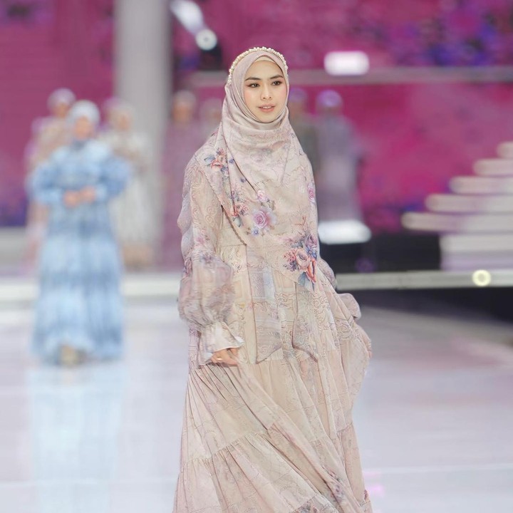 <p>Oki Setiana Dewi tampil memukau saat melenggang di panggung mode. Ia berpose di atas <em>runway</em> dengan mengenakan gamis motif beraksen<em> balloon sleeve</em> yang dipadu bersama hijab segi empat panjang. (Foto: Instagram @okisetianadewi)</p>