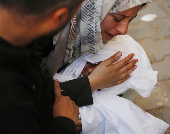 DEIR AL-BALAH, GAZA - FEBRUARY 18: (EDITORS NOTE: Image depicts death) A Palestinian family hugs the dead body of their child who died in an Israeli attack as Palestinians, who lost their lives including children, being taken to Al-Aqsa Martyrs Hospital while Israeli army's intense bombardment of the Gaza Strip continues in Deir al-Balah, Gaza on February 18, 2024. (Photo by Ashraf Amra/Anadolu via Getty Images)