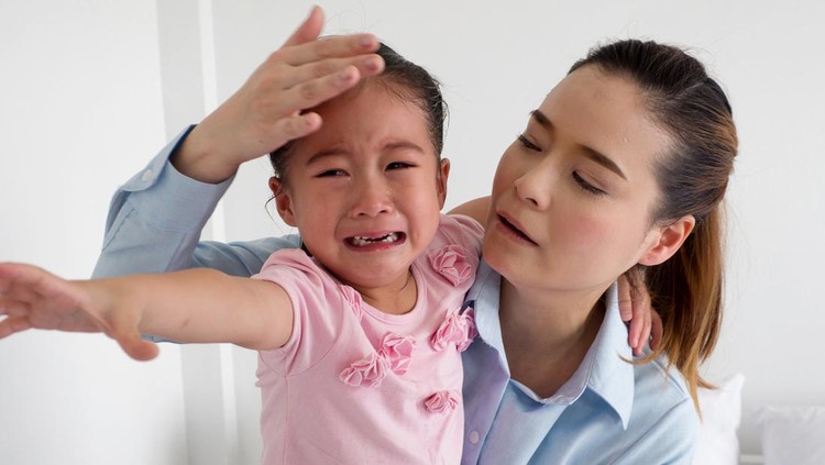Young mother holding her crying baby girl;
