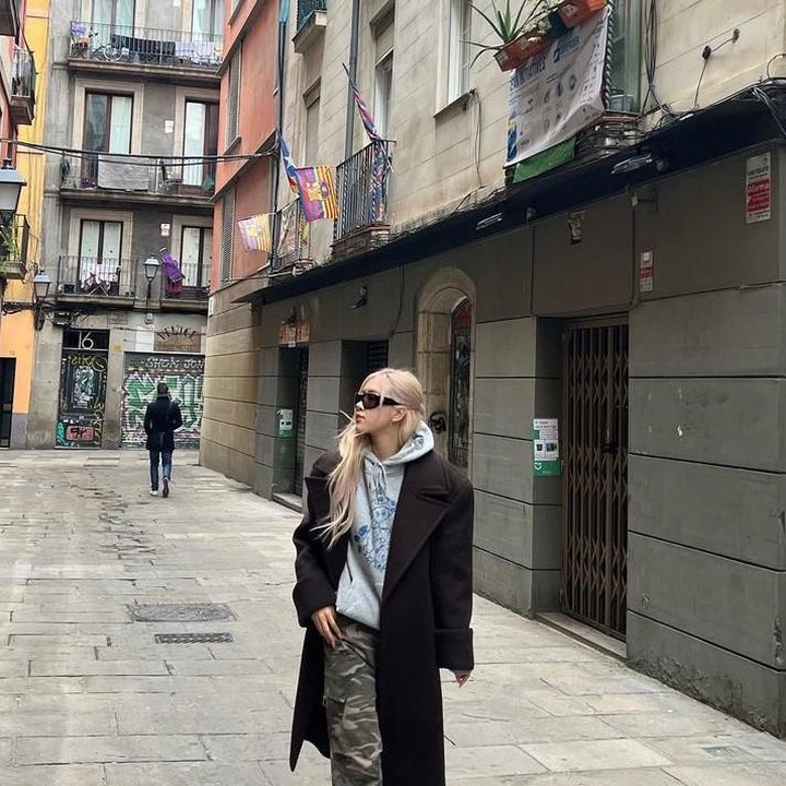 <p>Sedang jalan-jalan di Barcelona, Spanyol, Rose tampil dengan gaya kasualnya dengan memakai <em>hoodie</em> abu-abu dengan celana motif army dilengkapi coat berwarna hitam. (Foto: Instagram @roses_are_rosie)</p>
