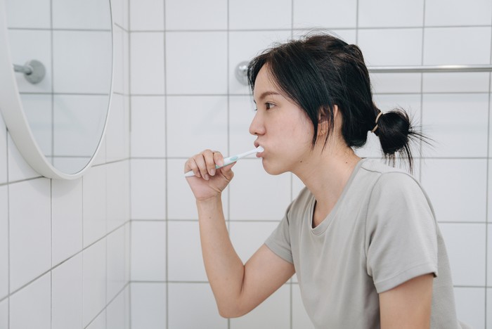 Asian Woman Cleaning Teeth With Toothbrush And Paste Doing Daily Oral Hygiene Routine In Bathroom At Home. Closeup Of Female Brushing Teeth.