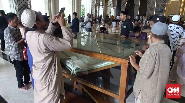 Alquran raksasa dengan ukuran 1 x 1,5 meter dan berat 584 kilogram yang dipajang di pintu masuk Masjid Raya Makassar menarik perhatian jemaah.