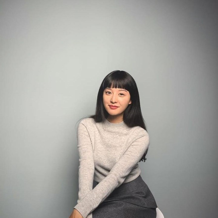 <p>Dengan gaya rambutnya yang manis, Kim Ji Won makin <em>girly</em> dengan atasan <em>turtleneck light grey</em> dan rok berwarna abu-abu gelap. (Foto: Instagram @geewonii)</p>