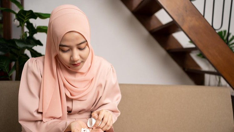 Young healthy Muslim woman holding pill. adult lady take daily medicine diet vitamin supplements for beauty skin hair health care medicament .