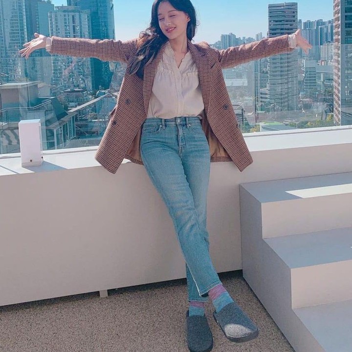 <p>Nah, kalau yang ini Kim Ji Won sedang menikmati pemandangan kota Seoul dengan gaya <em>chic</em>-nya. Ia mengenakan <em>checked blazer</em> dan <em>blouse</em> netral serta celana jeans berwarna biru. (Foto: Instagram @geewonii)</p>