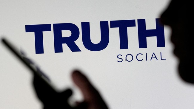 The Truth social network logo is seen displayed behind a woman holding a smartphone in this picture illustration taken February 21, 2022. REUTERS/Dado Ruvic/Illustration/File Photo