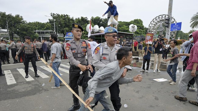 Aparat kepolisian membuat barikade usai dua kelompok massa bentrok saat melakukan aksi demonstrasi di Patung Kuda, Jakarta Pusat, Rabu (27/3).