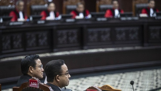 Anies Baswedan dan Muhaimin Iskandar tengah melihat layar besar ketika hakim Mahkamah Konstitusi mengetuk palu putusan sengketa hasil Pilpres 2024.