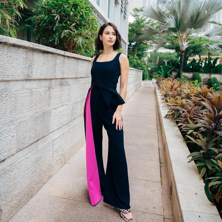 <p>Perempuan berusia 31 tahun itu juga memperlihatkan potret OOTD dengan memakai <em>jumpsuit</em> berpotongan asimetris. Warna <em>shocking pink</em> di antara <em>outfit</em>-nya yang didominasi oleh warna hitam memberi sentuhan <em>trendy, </em>nih. (Foto: Instagram @pevpearce)</p>