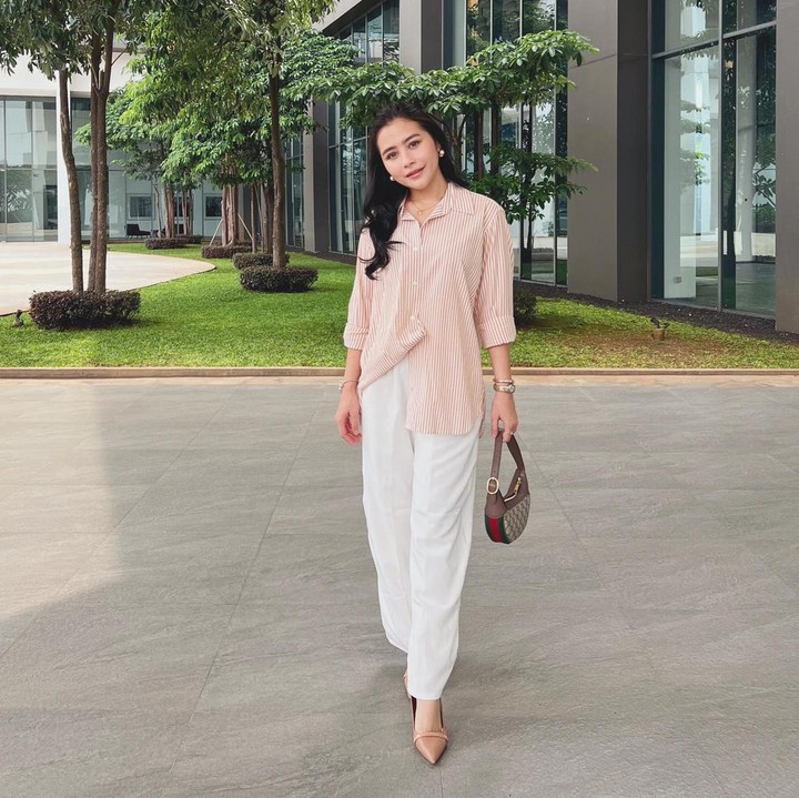 <p>Untuk Bunda yang gemar mengenakan warna cerah bisa mencoba kombinasi <em>loose shirt</em> warna peach dengan celana bahan warna putih. Sempurnakan penampilan Bunda dengan <em>pointy shoes</em>. (Foto: Instagram @prillylatuconsina96)</p>
